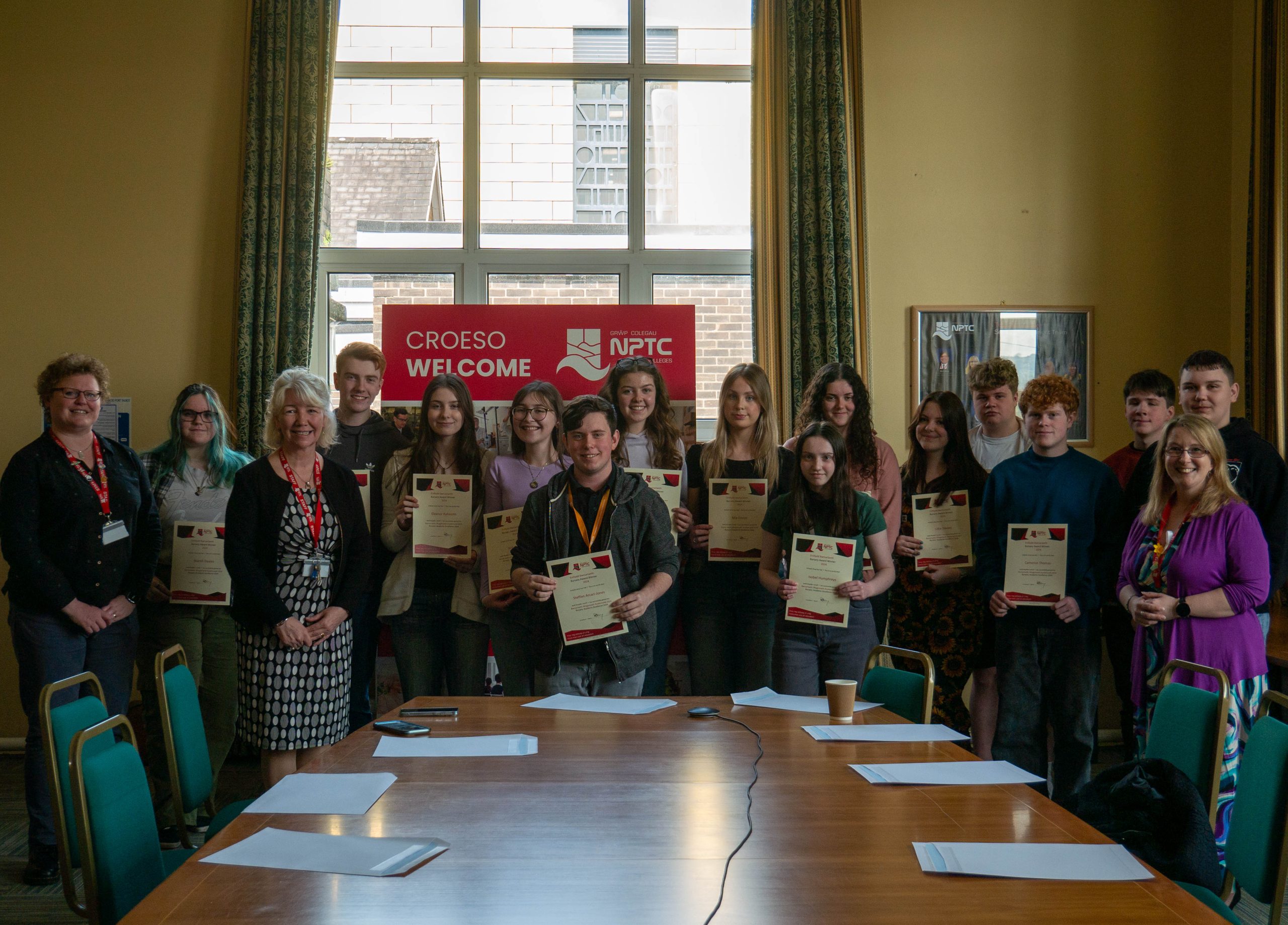 Bursary Award winners in a group with their certificates and members of staff around Boardroom table.