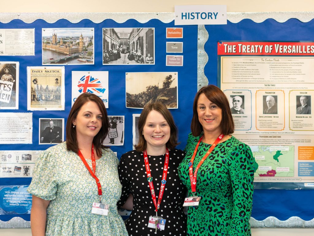 History Lecturers Kirsty Tompkins, Karen Jones, Alice Heath-Lawrence in front of a display board with students' work.