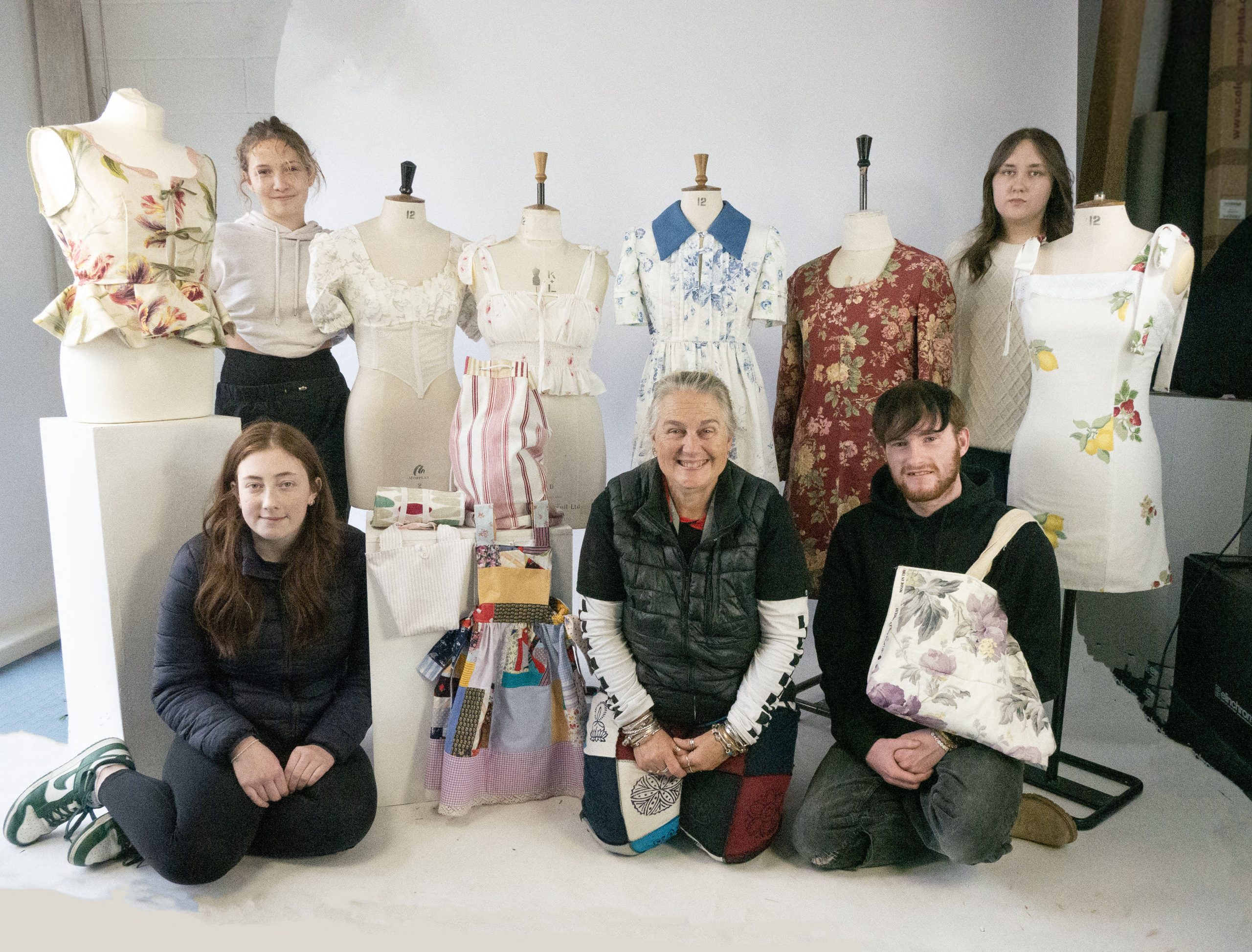 Students and lecturer posing with donated fabrics on mannequins.